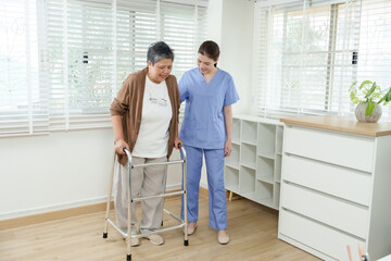 Senior asian woman using walker during home rehabilitation session guided by young asian female...