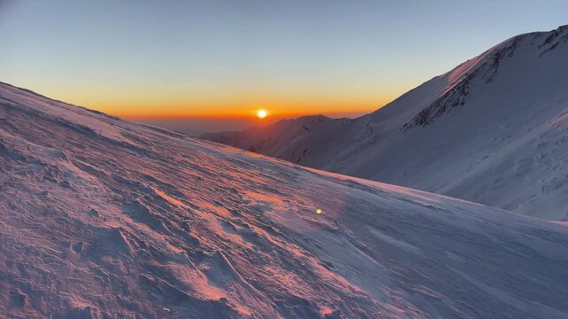 Summit push day beginning with incredible sunrise during Extreme expedition under famous Lenin peak (Ibn Sina Peak) 7134m. High altitude view with icy slope deep snow over clouds landscape.