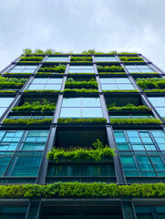 A low-angle shot of a high-rise building featuring extensive green walls covering the facade.