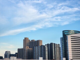 Fototapeta premium Modern high-rise buildings under a clear blue sky in the city at sunset. Captures contemporary urban architecture and peaceful skyline atmosphere.
