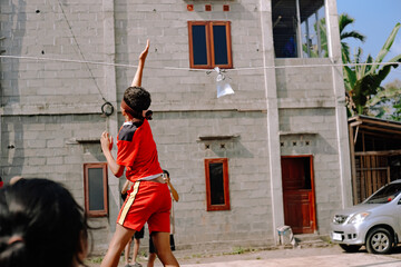 Boy playing traditional Indonesian game, trying to hit a plastic bag while blindfolded during...