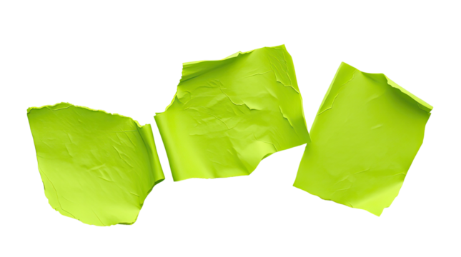 Three pieces of crumpled green paper are scattered on a white surface demonstrating a disorganized workspace often seen in creative settings