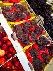 Freshly harvested grapes and apples displayed for sale at a local market in the afternoon sunlight