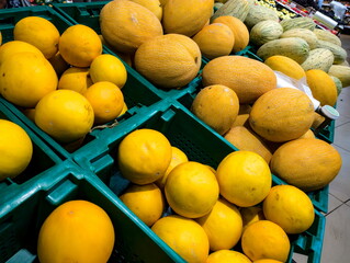 Fresh yellow melons and cantaloupes display in a grocery store in the afternoon light, inviting shoppers to explore their delicious options and make healthy choices