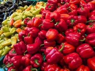 Colorful assortment of fresh bell peppers and chili peppers displayed at a local farmers market in the afternoon sun