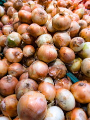 Freshly harvested onions piled high in a vibrant market, showcasing the variety and abundance of produce available for local shoppers and chefs