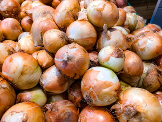 Freshly harvested onions piled in a market for sale showcasing their vibrant earthy tones and unique shapes, attracting customers looking for quality produce