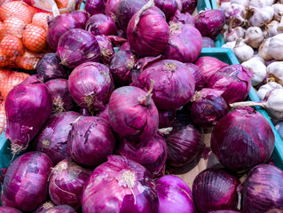 Fresh red onions and garlic displayed at a vibrant local market stall during the afternoon, inviting culinary enthusiasts to explore diverse flavors