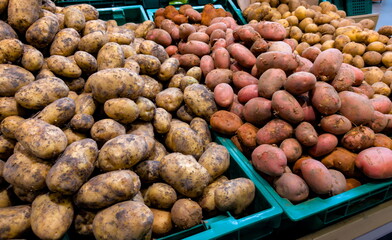 Various types of potatoes displayed in baskets at a market stall in the afternoon light of a local farmers market