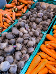 Vibrant market display featuring fresh carrots and beets during the afternoon at a local farmers market in a lively urban area
