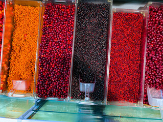 Display of colorful berries and fruits in transparent containers at a local market during daylight hours