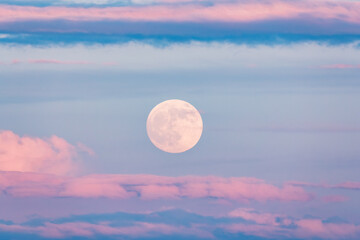 A lake with a cloudy sky and a full moon. The water is calm and the sky is overcast