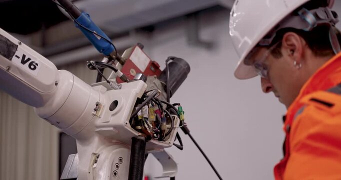 Slowmotion close up of industrial robotic joint wiring during collaborative diagnostics session in smart automation training for robot maintenance, repair and internal component inspection