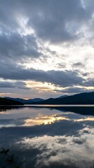 Fototapeta premium Calm lake at sunrise reflecting clouds