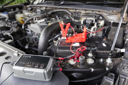 Man is charge a car AGM battery with a portable charger.