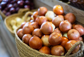 Close-up view of bulb onions placed in straw basket in outdoor grocery store