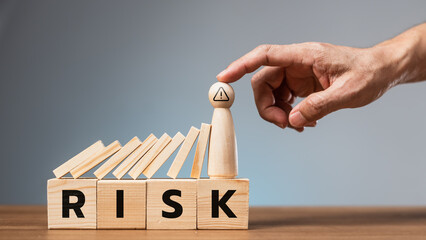 Risk management concept with wooden blocks falling and a hand stopping the last piece, symbolizing...