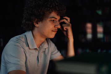 Focused young man working late on computer in dark room