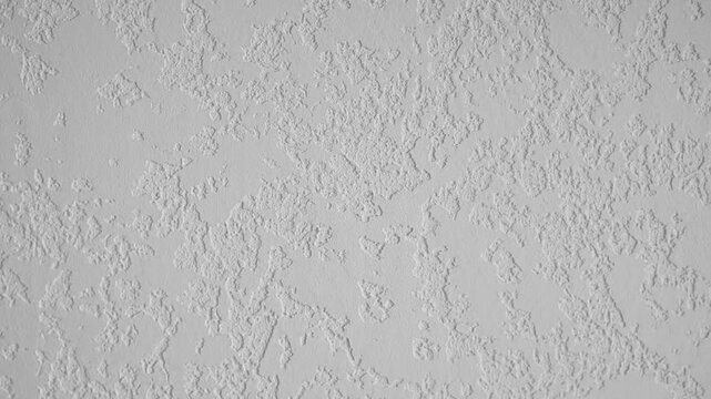 A bright white textured wall surface displays a rough bumpy pattern, creating an uneven background texture suitable for various design projects.