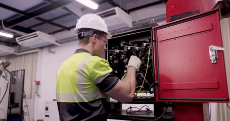 male technician performs slowmotion maintenance on industrial electrical cabinet inside smart factory using gloves and safety gear during automation training under industry40 engineering standard