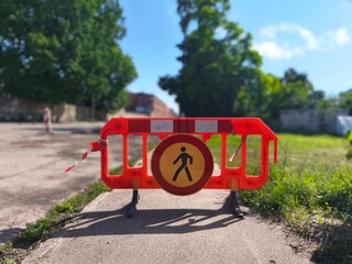 Red plastic barriers and no pedestrian sign block sidewalk during construction. Urban safety and...