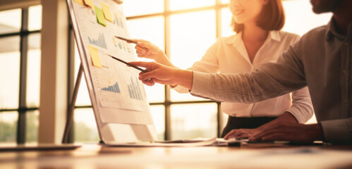 Two people discuss a project on a whiteboard in a bright office, exchanging ideas and mapping strategies during an engaging and dynamic business collaboration session.