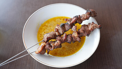 Sate Klatak, tender lamb satay skewered on bicycle spokes, served on yellow curry soup. Popular street food in Yogyakarta
