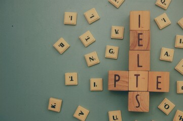 Wooden blocks with the word IELTS - International English Language Testing System and PTE = Pearson Test of English.