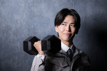 作業着でダンベルを持つ強い製造業のイメージ　クローズアップ