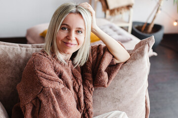 Cut Middle aged Woman sitting on couch at home