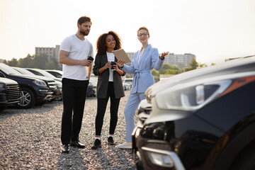 Obraz premium A car salesperson assisting a couple in selecting a new vehicle at a car dealership, outdoors.