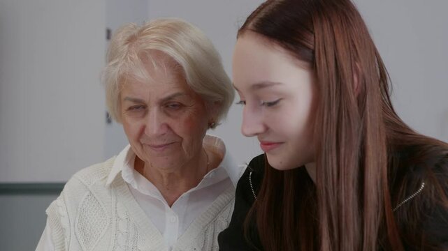 Granddaughter patiently guiding elderly grandmother through smartphone features, bridging generation gap with warmth and digital literacy understanding