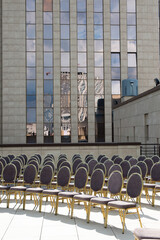 Chairs arranged in rows for a formal event against a backdrop of modern architecture.