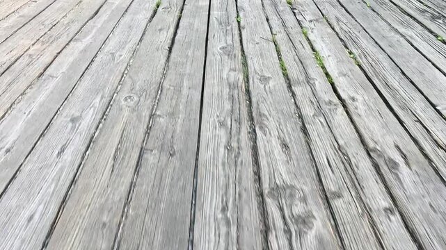 Old wooden deck boards display natural weathering effects with visible grain patterns and aging textures creating rustic outdoor flooring surface with natural wood color variations