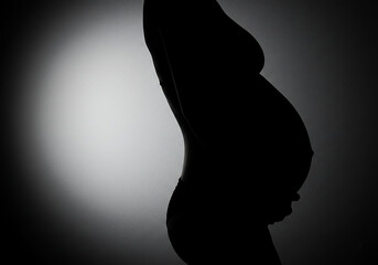 Silhouette of a pregnant woman against a light
