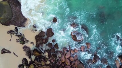 Stunning ocean waves crash against rock formations on sandy beach creating dynamic movement and scenic beauty from aerial view - Powered by Adobe
