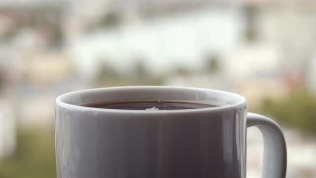 Sugar cube dropped into coffee mug with blurred skyline and splash motion, used in branded beverage contexts with city backdrops