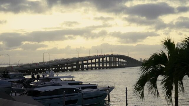 Downtown Miami And Key Biscayne Rickenbacker Causeway Bridge At Dusk With Marina Yachts And Waterfront Skyline Sunset