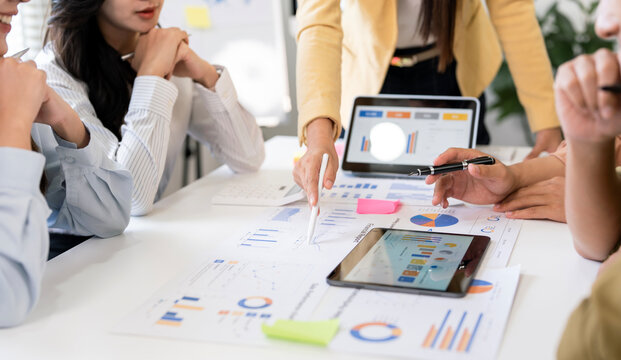 Close-up of business people discussing financial data and charts during a team meeting with tablets and calculator in modern office.