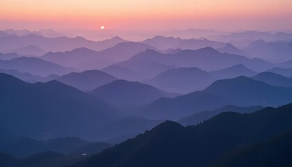 Fototapeta premium Layered mountain ridges fading into a purple and pink horizon at sunrise