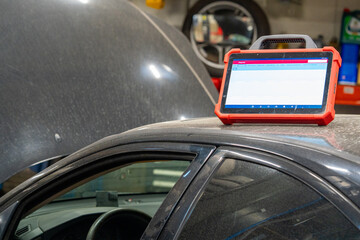 Digital diagnostic scanner tablet on a vehicle in an auto repair garage, with an extensive tire...