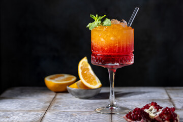 Sunrise cocktail in a tall glass with a straw, pomegranate, orange, crushed ice