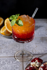 Sunrise cocktail in a tall glass with a straw, pomegranate, orange, crushed ice