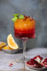 Sunrise cocktail in a tall glass with a straw, pomegranate, orange, crushed ice