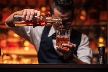 Bartender is pouring whiskey into a glass in a restaurant