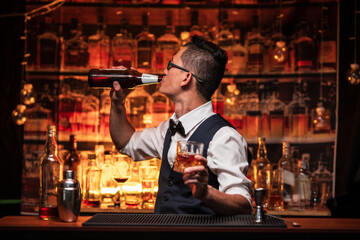 Bartender pours himself a glass of whiskey in a restaurant.