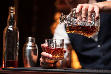 Bartender is pouring whiskey into a glass in a restaurant