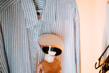 Woman steam cleaning a shirt in her home to remove wrinkles and refresh fabric