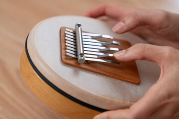 Hands of a woman playing the Hokema Sansula musical instrument.