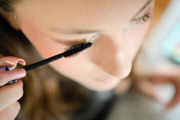 Close-up photo of a teenage girl applying mascara to enhance her eyelashes. Young, stylish girl...